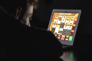 Gambling addicted man with glasses in front of online casino slot machine on laptop computer at night stock photo