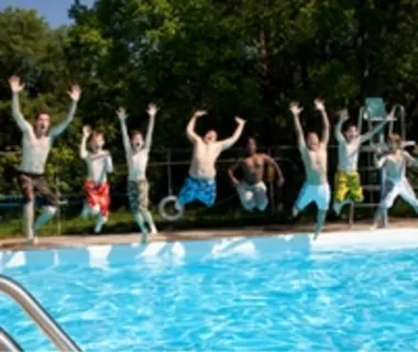 Group of youth jumping into an outdoor pool