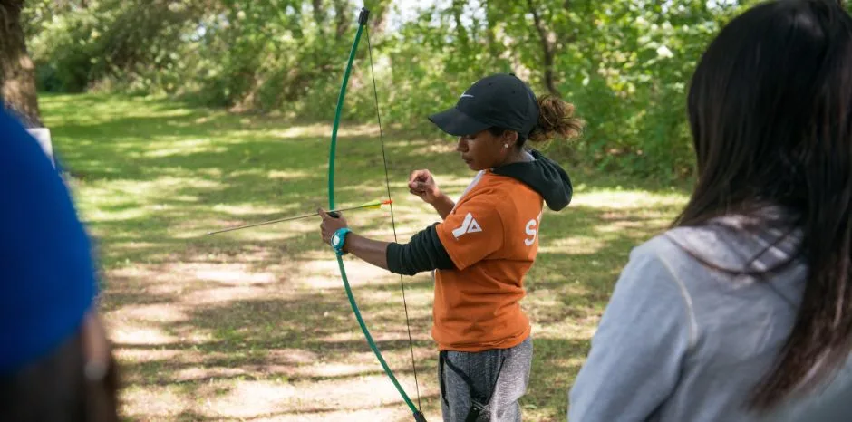 YMCA staff teaching kids archery