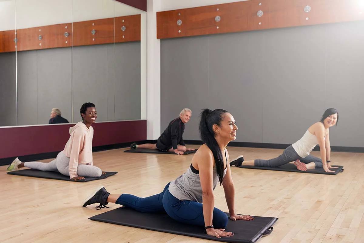 Ladies Holding Yoga Mats Chatting Before A Class One Lady In The