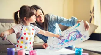 child shows colourful painting to mom