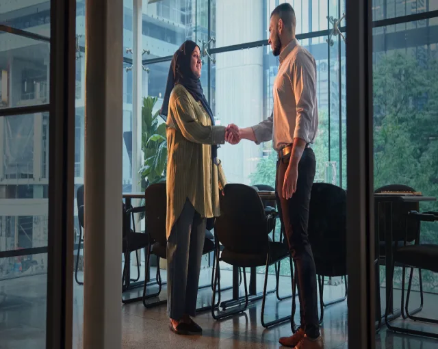 A newcomer engaged in a handshake with a YMCA Immigrant Services employee.