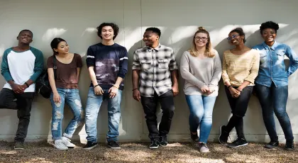 a diverse group of youth standing against a wall