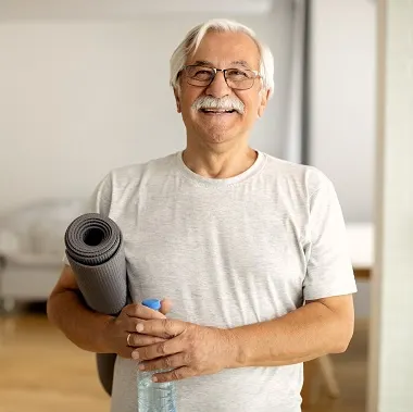 older man at home with yoga mat