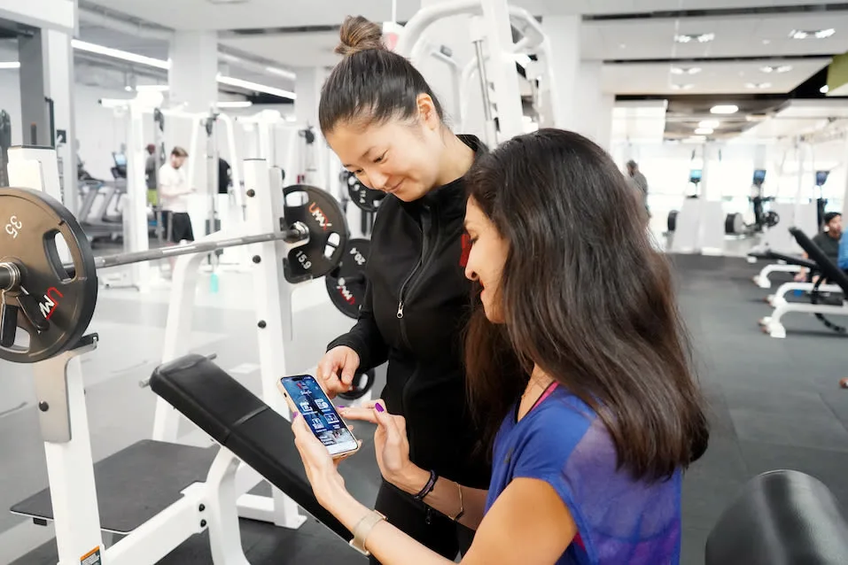 Two people look at the YGTA Shine On Health & Fitness App on a smartphone