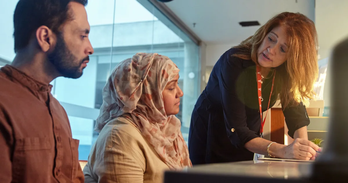 A YMCA employee consults with a couple at a YMCA Immigrant Services office.