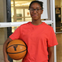 Crystal holding a basketball under her arm in the Mississauga YMCA gym
