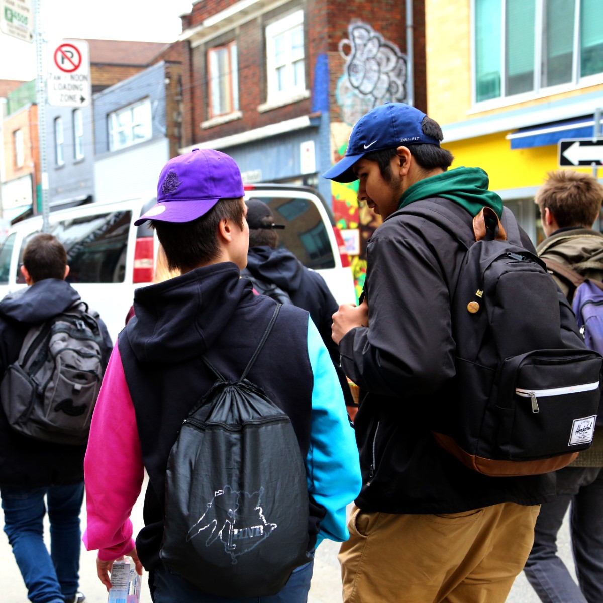 Two youth walking and talking during tour of Kensington market. April 16, 2019. Photo by Sarah Cowan. 