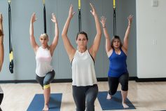 Group of people in a yoga class with arms over head in a lunge