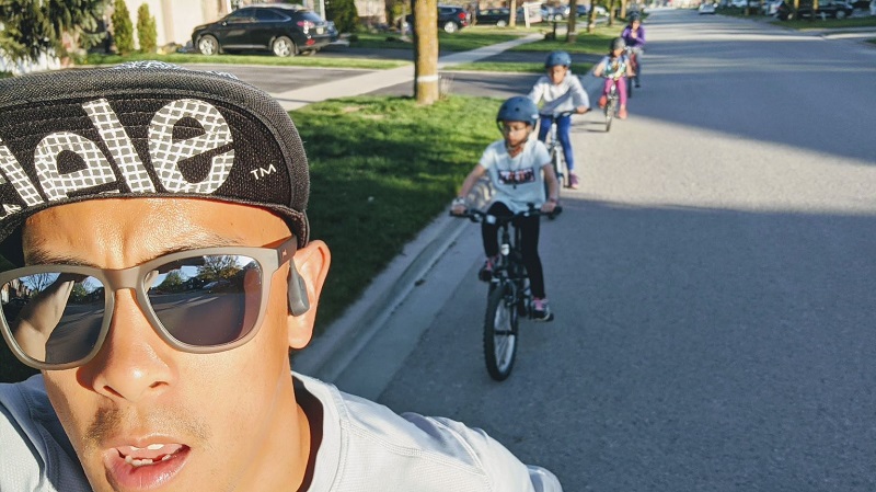 Man takes a selfie on his bike showing kids on bikes behind him