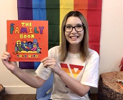 Y staff Jen holding The Family Book wearing a Y Pride t-shirt