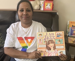 Y staff Sujatha holds the book "I am Jazz" wearing a Y Pride t-shirt