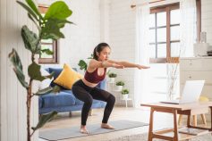Women does squats in her living room along with a class on the Sweat For Good app