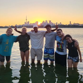 Group of youth with water to their knees in front of sunset on a city