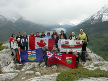 Group of youth and educator holding Canadian flags in front of mountain scenery